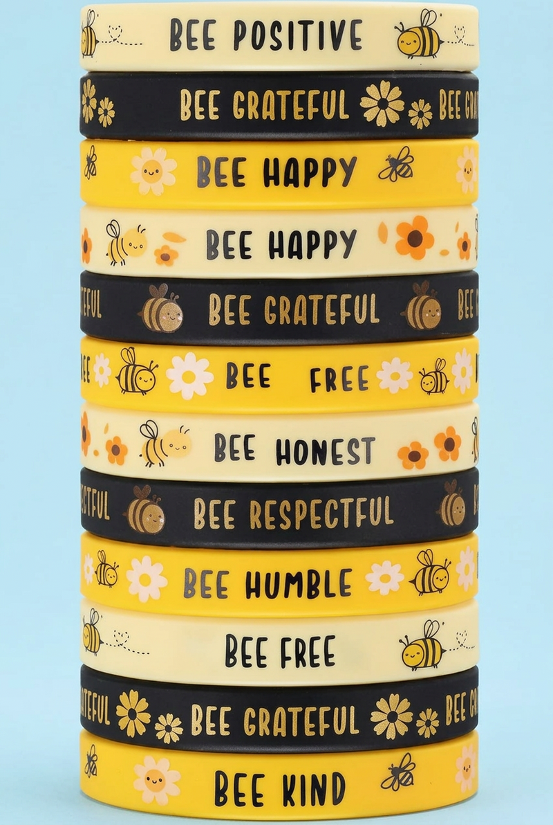 Three stacks of yellow and black bee-themed bracelets with motivational text like 'BEE HAPPY,' 'BEE GRATEFUL,' 'BEE FREE,' and 'BEE KIND' on a white background.
